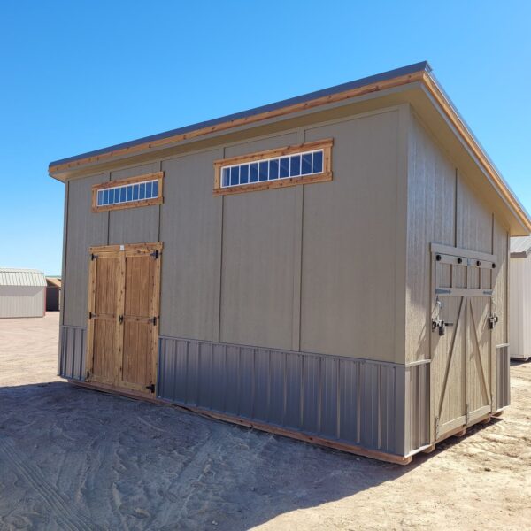 Large Royal Gorge style storage shed viewed from the front with double doors and ramp door on the side. Grey wooden walls with two wide short windows at the top.
