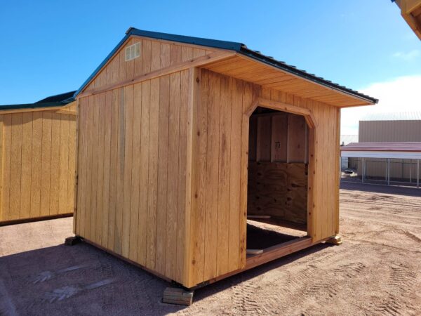 10x12 Loafing Style Storage shed on blocks. Large open entrance, wooden walls, metal roof.