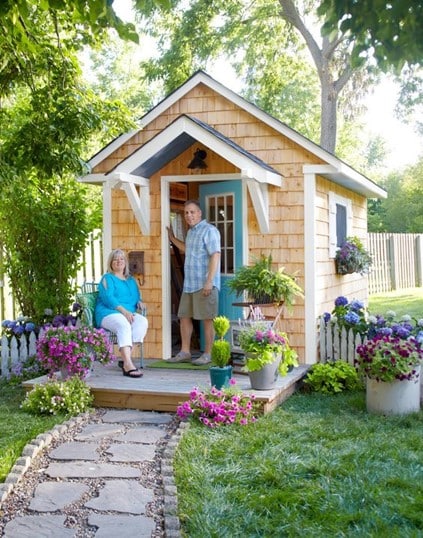 A homeowner couple enjoying their 10x12 storage shed, surrounded by plants.