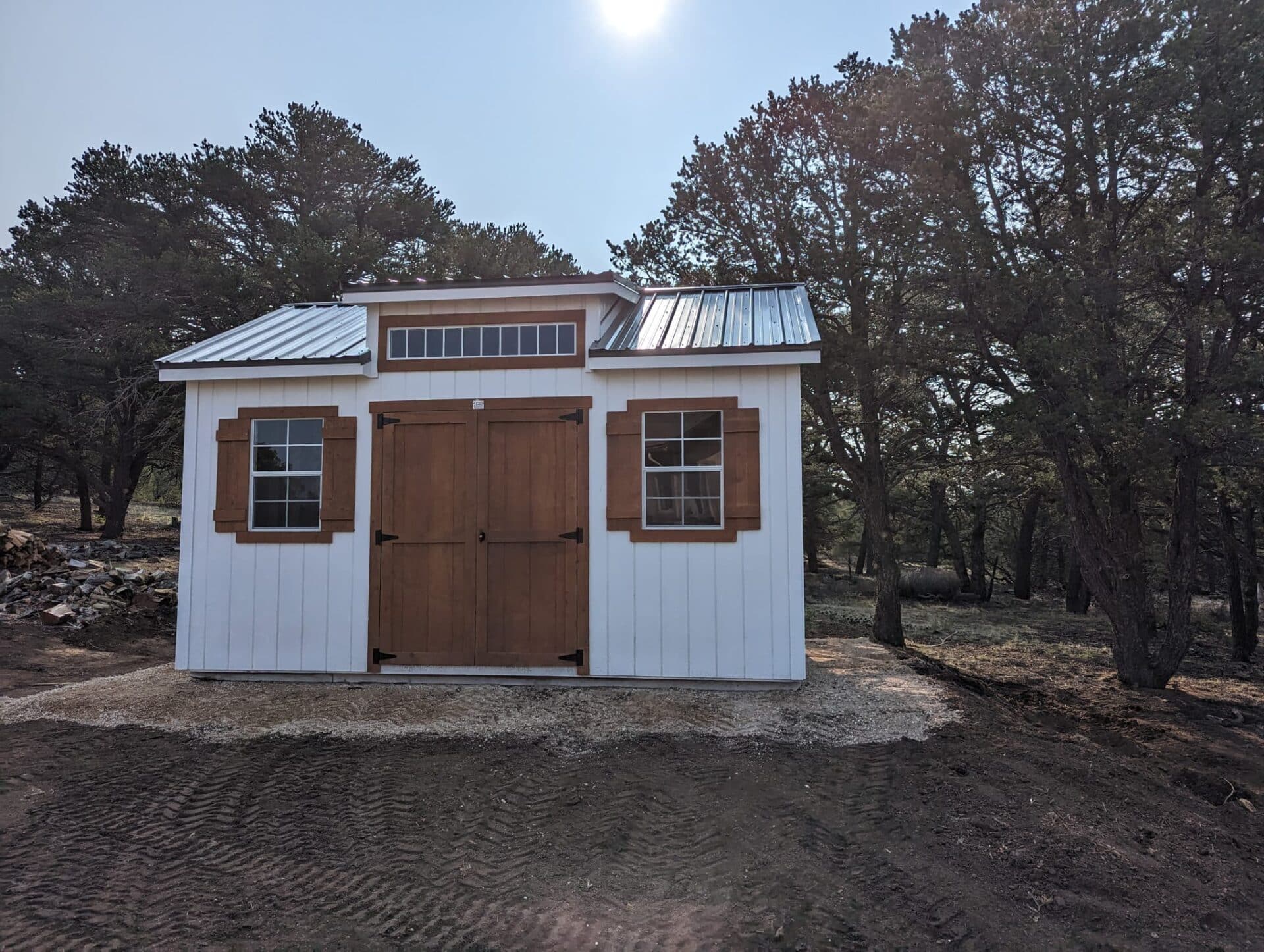 Front view of 12x16 Studio Gable in Cotopaxi, CO with three windows and double doors, wood trim with white walls.