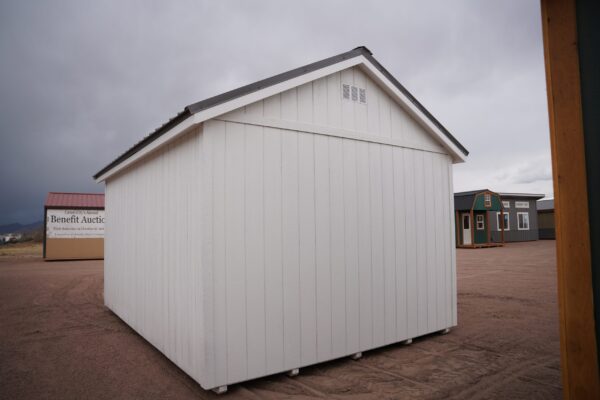 The sky is dotted with clouds as a 12x16 Studio Gable storage shed stands in the foreground of the picture.