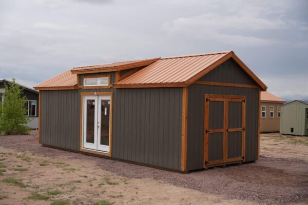 Studio Gable 12x28 storage shed viewed from the front corner, showing both sets of doors, grey wood siding, and two windows.