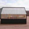 Side view of an 8x12 Green House with wood frame, green metal siding and roof, and plastic covering on the upper walls.