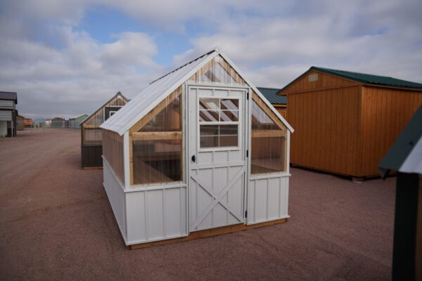 Front view of an 8x12 Green House with wood frame, metal siding and roof, and plastic covering on the upper walls.