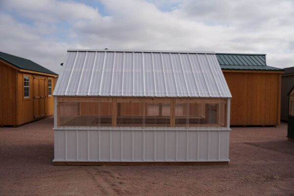 Side view of an 8x12 Green House with wood frame, metal siding and roof, and plastic covering on the upper walls.