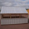 Side view of an 8x12 Green House with wood frame, metal siding and roof, and plastic covering on the upper walls.