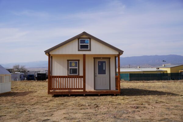 Gable storage shed w/ Porch 14x32 prepared for a more residential use, viewed from the front, highlighting the door, porch, and two windows