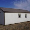 Gable storage shed w/ Porch 14x32 prepared for a more residential use, viewed from the back left corner, showing three windows and part of the porch.