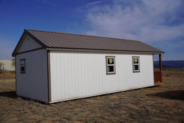 Gable storage shed w/ Porch 14x32 prepared for a more residential use, viewed from the back left corner, showing three windows and part of the porch.