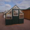 Front view of an 8x8 Green House with wood frame, metal siding, and plastic covering on the upper walls