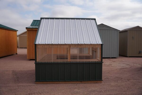 Side view of an 8x8 Green House with wood frame, metal siding and roof, and plastic covering on the upper walls.