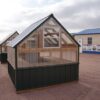 Back view of an 8x8 Green House with wood frame, metal siding, and plastic covering on the upper walls, showing the window in the back.