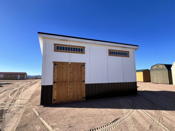 10x20 Royal Gorge Style storage shed with black metal wainscoting, white walls, wooden double doors and short wide windows at the top.