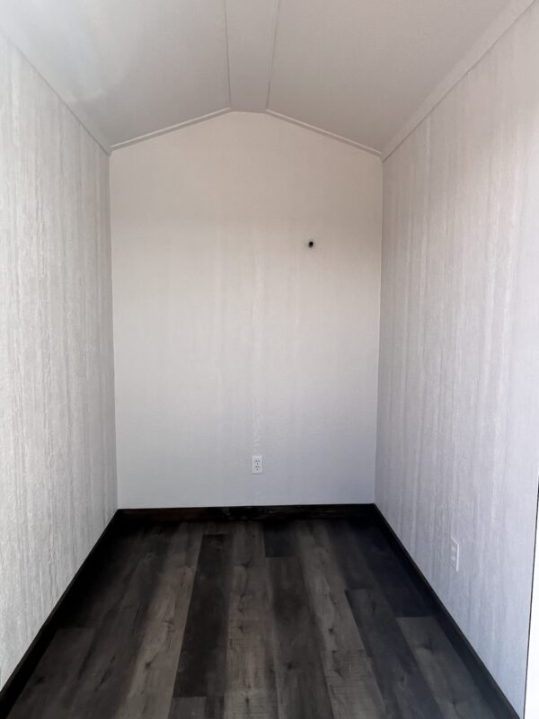 The nice interior of a 6x8 Gable Style storage shed with Interior Finish, with outlets, white finished walls and panelled flooring.