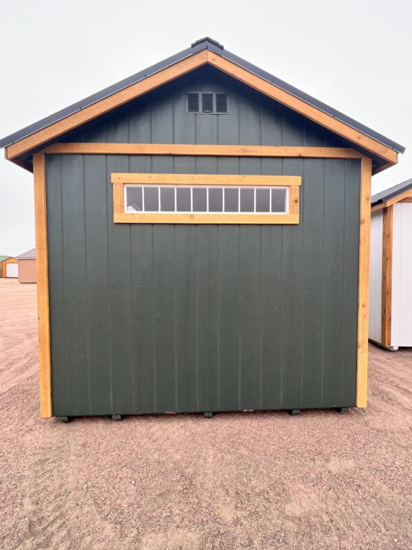 The sky stretches above a property with a shed, building, and garage, all with open doors.