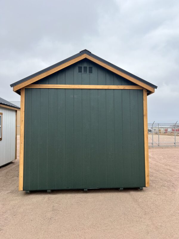 The sky is filled with clouds as a shed and building stand on the outdoor property, the door of the garage open.