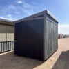 A view of the back side of the 8x12 Urban Style storage shed, showing the angled roof and wood paneling on the walls.