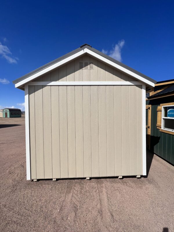 Discover the practicality of our 10x16 Gable storage shed as you observe it from the side, providing a view that emphasizes its sturdy tan-colored wooden walls and a sleek dark grey metal roof. This reliable structure ensures long-lasting durability and ample storage space, perfect for organizing your belongings.