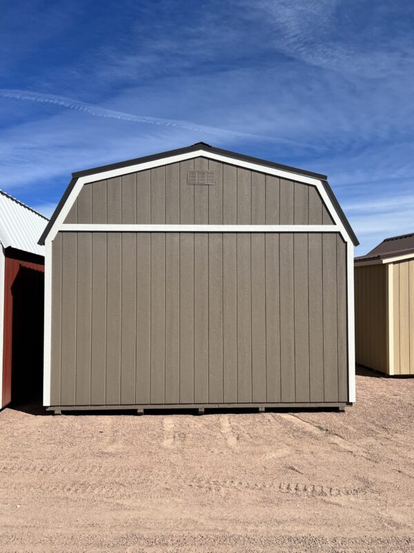 Behold the rear view of our expansive 14x32 Barn Style storage shed, showcasing its resilient beige wooden siding and commanding dark grey roof. This sturdy and spacious structure offers ample storage capacity while maintaining an elegant and timeless appeal, making it an ideal solution for accommodating your diverse storage requirements with style and durability.