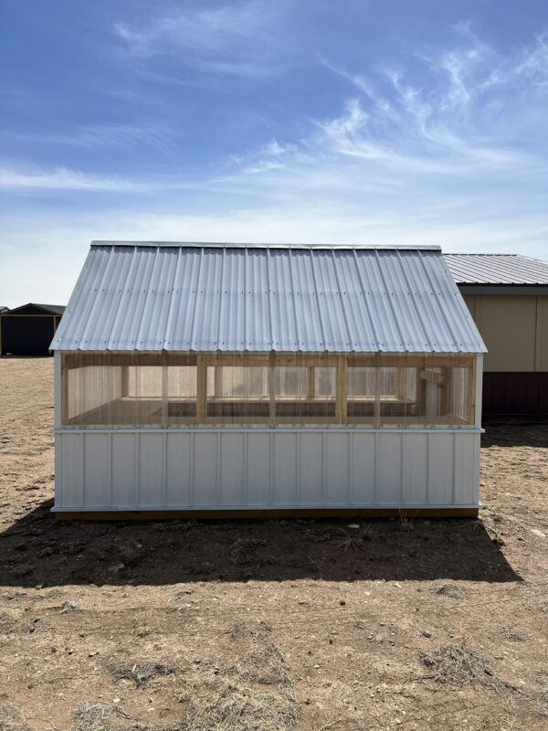 A 8x12 Greenhouse stands in the middle of a field, viewed from the side.
