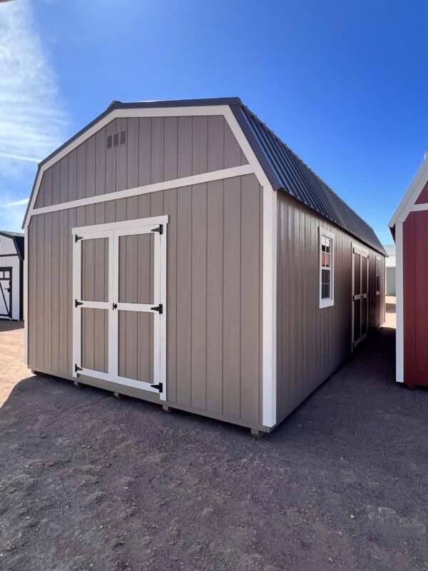 Take in the impressive front view of our substantial 14x32 Barn Style storage shed, prominently displaying its double doors that provide convenient access to the spacious interior. The combination of beige wooden siding and a dark grey roof creates a visually striking contrast, resulting in a captivating and functional storage solution that seamlessly integrates with your outdoor space.