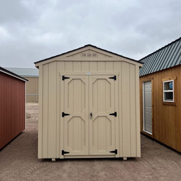 The sky is dotted with clouds as a wooden shed with a door stands in the outdoor property of a house.