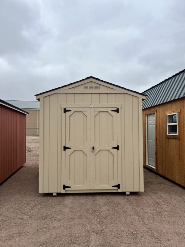 The sky is dotted with clouds as a wooden shed with a door stands in the outdoor property of a house.