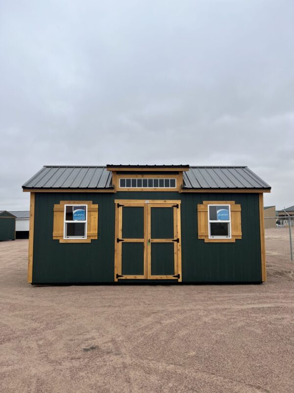 The sky is dotted with clouds as a building with a window and a property shed stands in the outdoor area of a house.