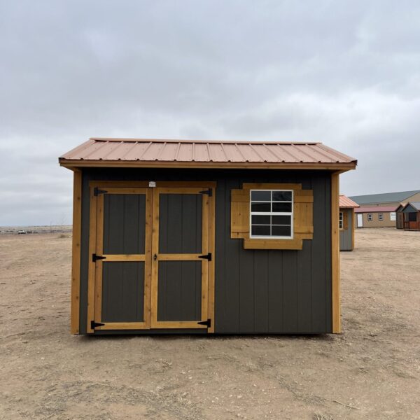The sun shines through a window of a beach house, illuminating a sandy property with a shed and a building surrounded by a cloud-filled sky.