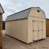 The sky is dotted with clouds as a large wooden shed with a door stands on the outdoor property.