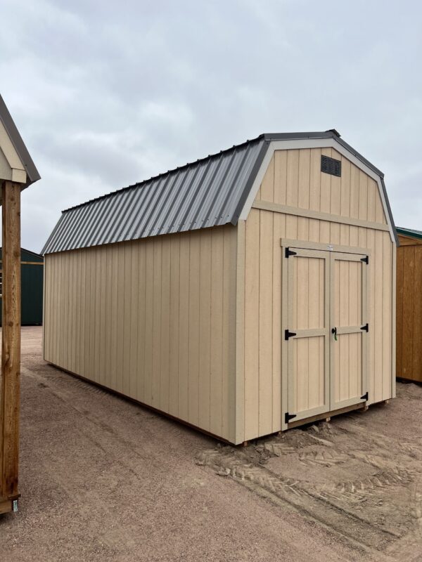 The sky is dotted with clouds as a large wooden shed with a door stands on the outdoor property.
