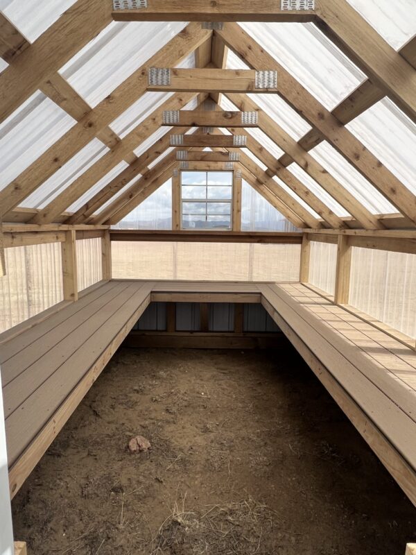 A beam of daylighting illuminates the 8x12 Greenhouse, highlighting the wooden roof constructed with lumber and composite material.