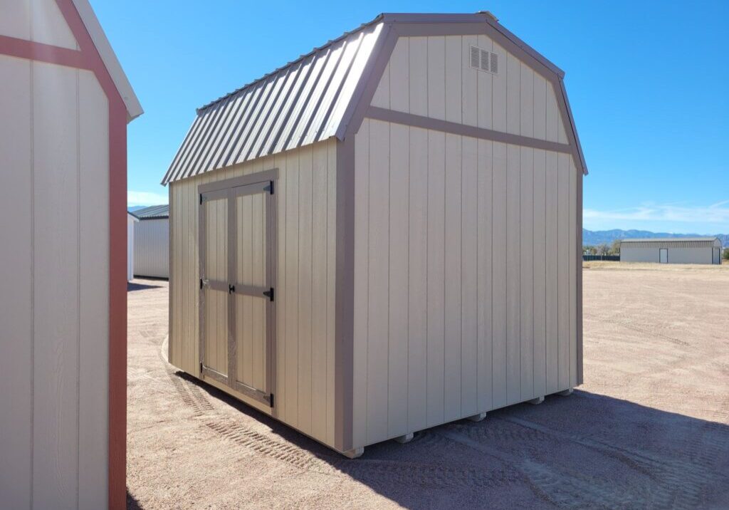 Barn style storage shed with tan walls and metal roof. Double doors, great for a garden shed or other storage uses.