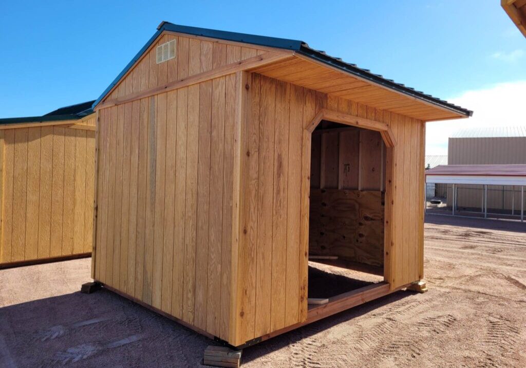 10x12 Loafing Style Storage shed on blocks. Large open entrance, wooden walls, metal roof.