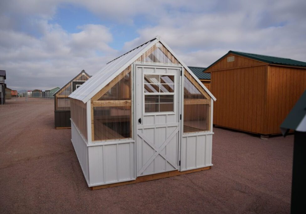 Front view of an 8x12 Green House with wood frame, metal siding and roof, and plastic covering on the upper walls.