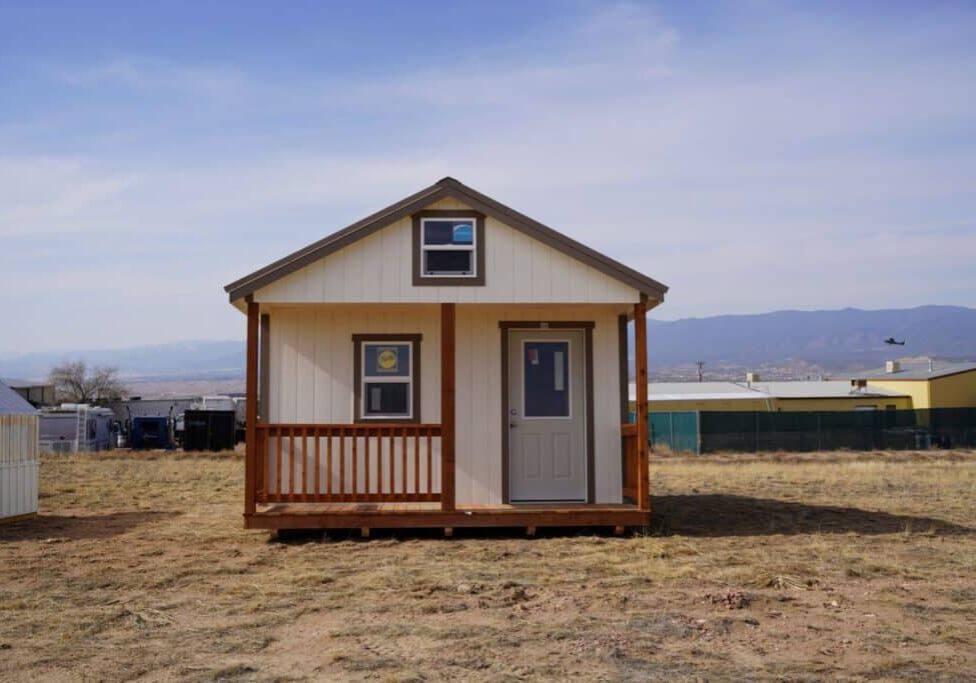 Gable storage shed w/ Porch 14x32 prepared for a more residential use, viewed from the front, highlighting the door, porch, and two windows