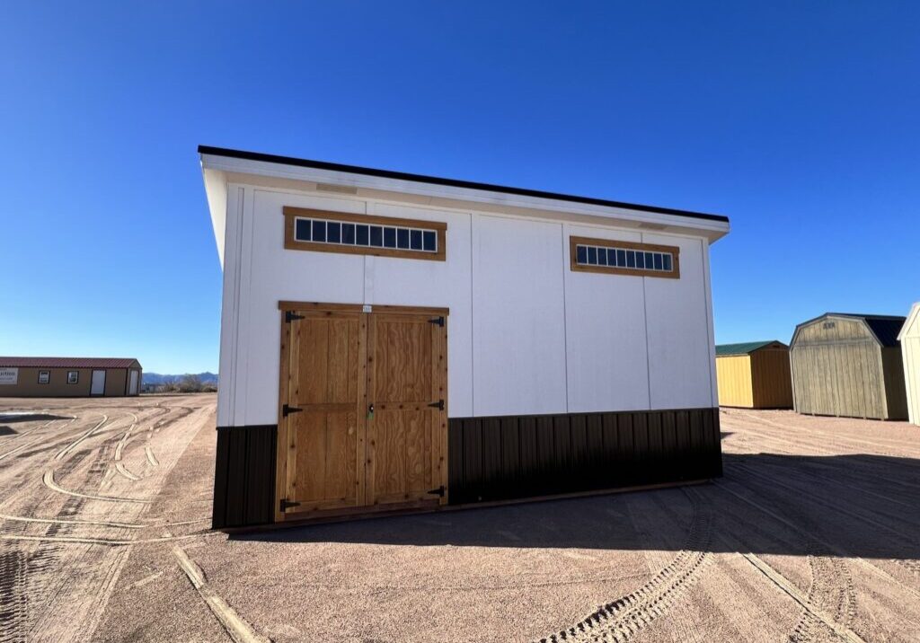 10x20 Royal Gorge Style storage shed with black metal wainscoting, white walls, wooden double doors and short wide windows at the top.
