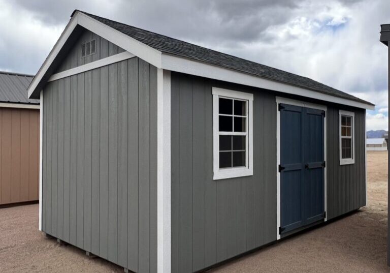 A view from the front corner of a 10x20 Gable Style storage shed with grey walls and big blue-grey swinging doors.