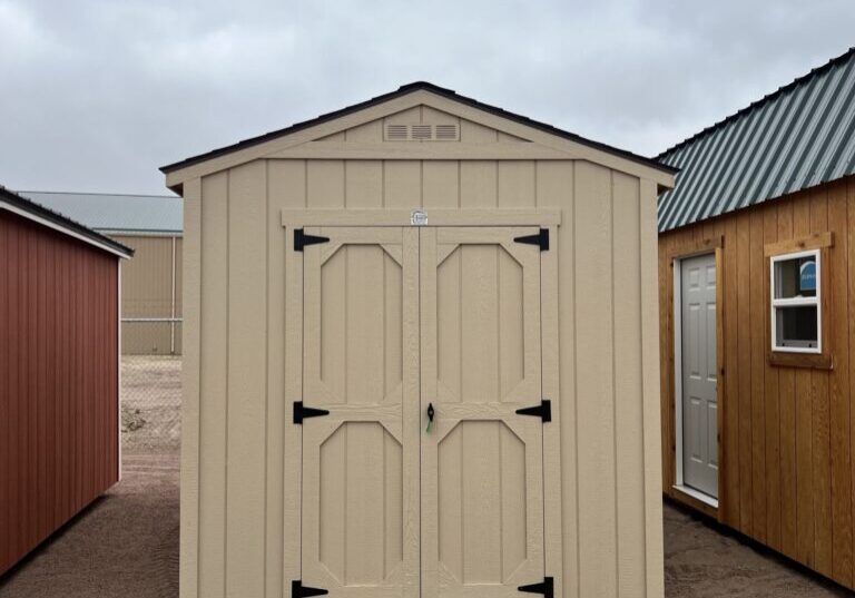 The sky is dotted with clouds as a wooden shed with a door stands in the outdoor property of a house.