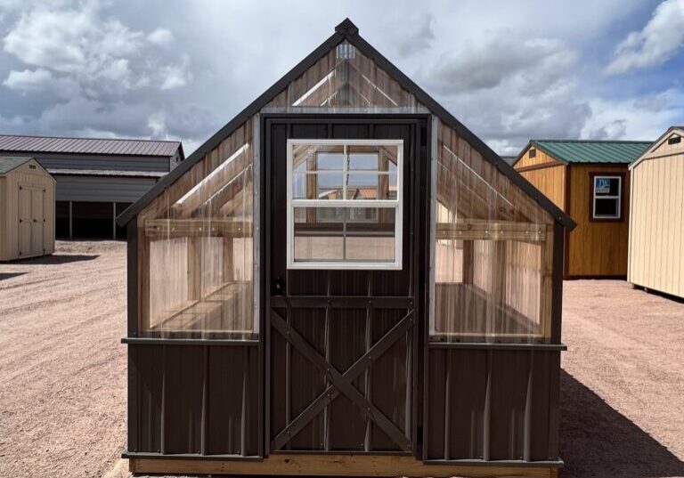 A view of the 8x8 Greenhouse, showing the large door in the front. In the background are several other storage sheds.